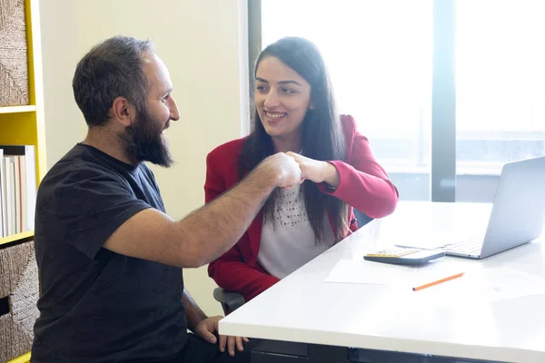 Business team bumping fists, after successful work business team bumping fists to celebrate. Caucasian, millennial businessman and businesswoman team spirit concept photo in office with copy space.