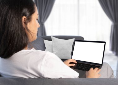 Holding laptop, young caucasian woman relaxing on sofa holding laptop at home. Computer mock up blank white screen. Using modern notebook, watching movie, online learning, surfing internet, read news.