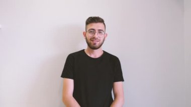 Portrait of young man looking camera isolated white background. Young caucasian brown haired and stubble bearded boy posing camera. Handsome male wearing casual front view studio 4k footage.