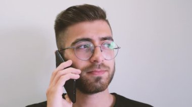 Talking mobile phone, front view of young man talking mobile phone. Caucasian, generation z, brown haired teenage boy wearing glasses looking in the window and having a conversation