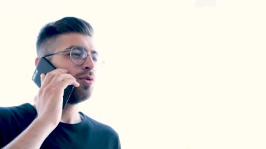 Telefonla konuşmak, genç adamın telefonla konuşurken çekilmiş görüntüleri. Genç kahverengi saçlı gözlüklü çocuk. Stresli erkek hızlı konuşuyor, etrafa bakıyor, hayal kırıklığına uğramış erkek akıllı telefon kullanıyor..