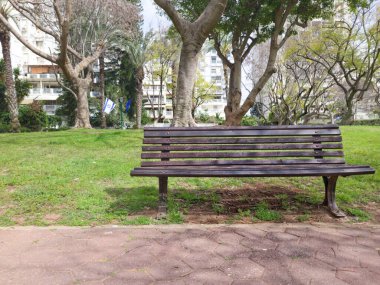 Parkın dışındaki ahşap bankta.