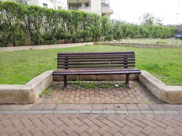 Parkın dışındaki ahşap bankta.