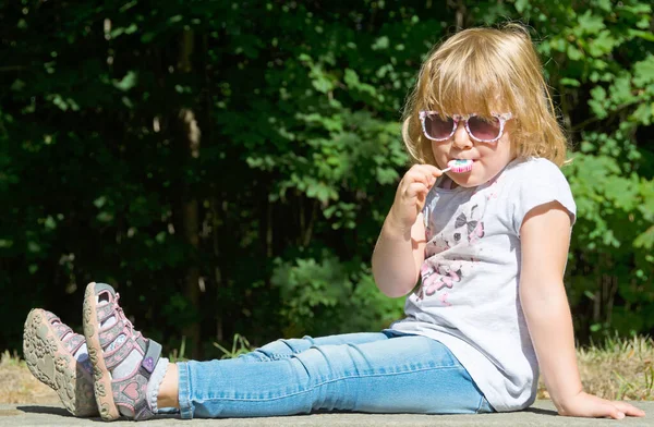 Sweet Child Sitting Park Bank Outdoors Sucking Lollipop — Stock fotografie