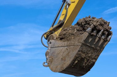 Excavator shovel in front of blue sky