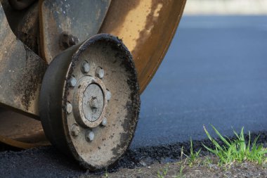 Toprak asfaltlama yoluyla mühürleniyor. Yakın planda yol silindiri.
