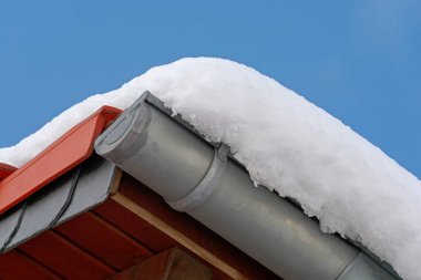 Güneşli bir günde, arka planda mavi gökyüzü olan karlı çatı.