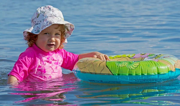 Toddler playing alone with a swim ring in the lake