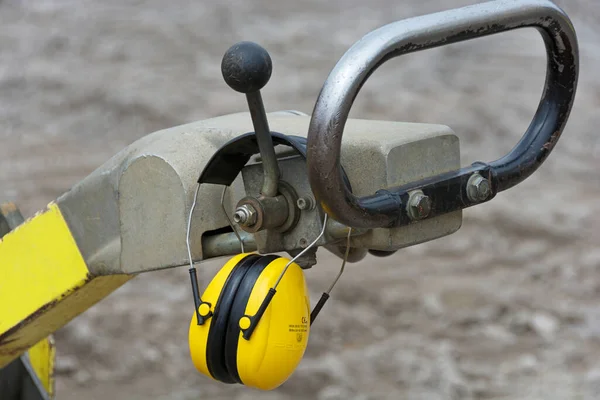 Hearing protection hanging on vibrating plate - noise protection on the construction site