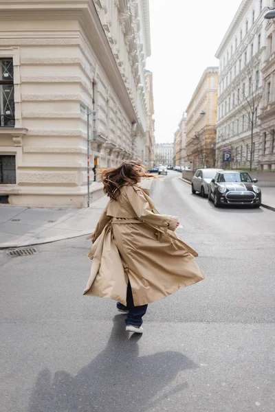 Mladá Žena Trench Kabát Třesoucí Hlavou Při Chůzi Evropském Městě — Stock fotografie