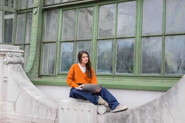 Ung Kvinna Jeans Och Orange Kofta Med Bärbar Dator Taket — Stockfoto