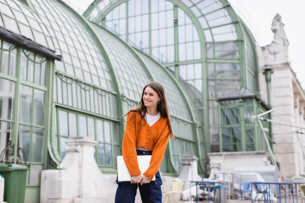 Pleased Young Woman Jeans Orange Cardigan Standing Laptop Rooftop Building — Stock Photo, Image