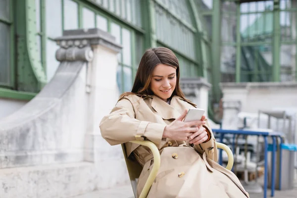 Vrolijke Vrouw Stijlvolle Trench Jas Met Behulp Van Mobiele Telefoon — Stockfoto