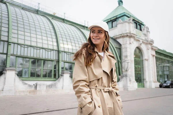 Pleased Young Woman Trench Coat Baseball Cap Standing Hands Pockets — ストック写真