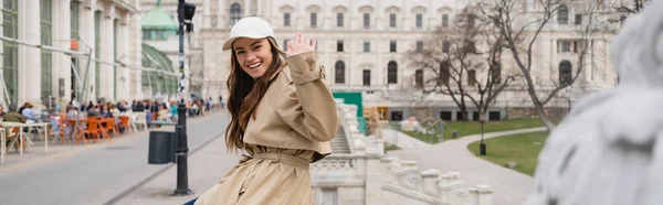 Mujer Joven Feliz Con Elegante Gabardina Gorra Béisbol Agitando Mano — Foto de Stock