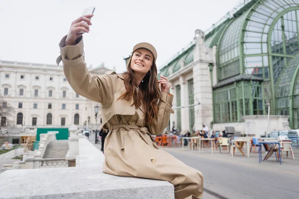 Glückliche Junge Frau Stylischem Trenchcoat Und Baseballmütze Macht Selfie — Stockfoto