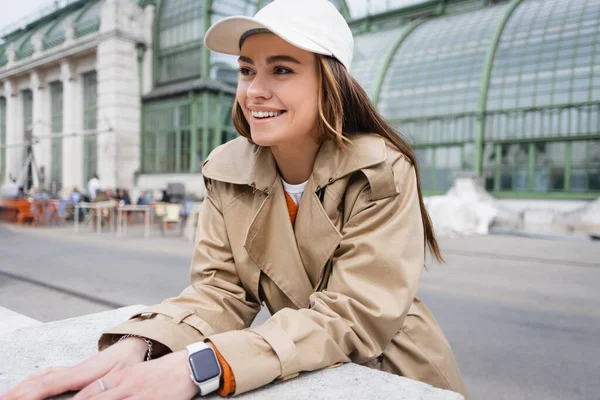 Joyful Young Woman Beige Trench Coat Baseball Cap Looking Away — ストック写真