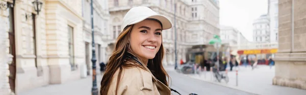Trençkotlu Beysbol Şapkalı Neşeli Kadın Avrupa Şehrinin Caddesinde Afiş — Stok fotoğraf