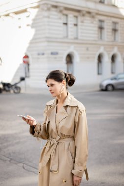 Telli kulaklıklı bir kadın elinde cep telefonu, Viyana 'da sokakta müzik dinliyor.