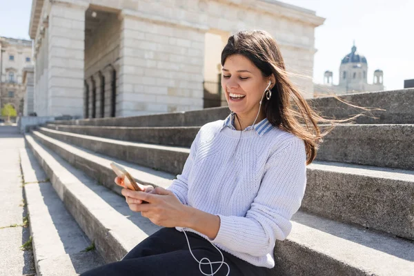 Cheerful Woman Listening Music Wired Earphones Using Smartphone While Sitting — Stock Photo, Image