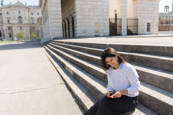 Usmívající Žena Poslech Hudby Drátových Sluchátkách Pomocí Smartphonu Při Sezení — Stock fotografie