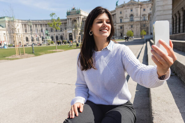 happy woman taking selfie on smartphone in vienna 