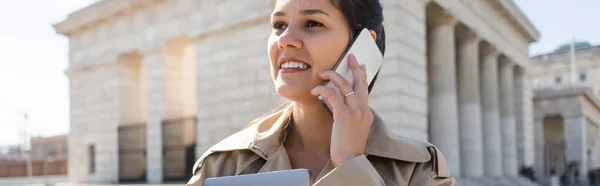 トレンチコートを着た陽気な女性が外のスマートフォンで話しバナー — ストック写真