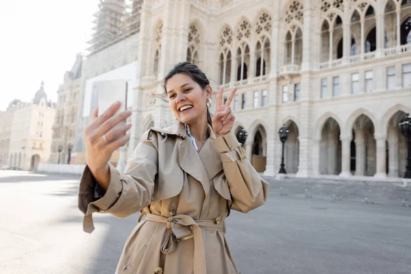 Mujer Feliz Gabardina Beige Mostrando Señal Paz Tomando Selfie Cerca —  Fotos de Stock