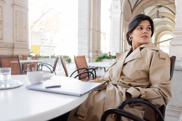 Γυναίκα Καμπαρντίνα Κάθεται Κοντά Στο Laptop Και Ποτά Στην Καφετέρια — Φωτογραφία Αρχείου