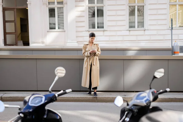 ウィーンの路上で携帯電話を持ち音楽を聴いている有線イヤフォンの女性の — ストック写真