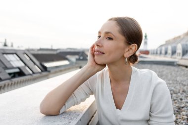 thoughtful woman smiling while looking away on rooftop