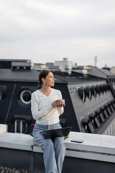 Kobieta Glinianym Kubkiem Siedzi Dachu Pobliżu Laptopa Telefonu Komórkowego — Zdjęcie stockowe