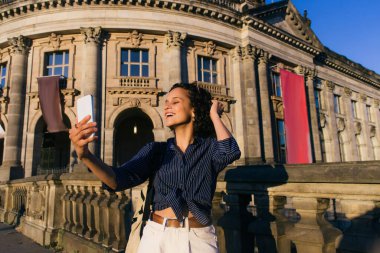 cheerful young tourist taking selfie near bode museum in berlin  clipart