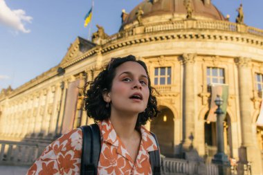 surprised young woman standing near bode museum in berlin  clipart