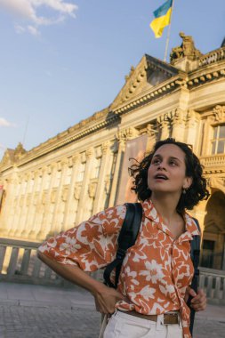 surprised young woman in sunglasses standing near bode museum with ukrainian flag 