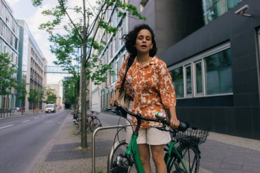 amazed young woman in summer outfit standing near bicycle in berlin 