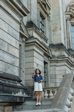 full length of tourist taking selfie on smartphone in front of building in berlin 