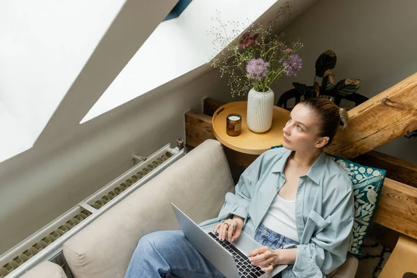 Wysoki Kąt Widzenia Kobiety Patrząc Okno Podczas Korzystania Laptopa Kanapie — Zdjęcie stockowe