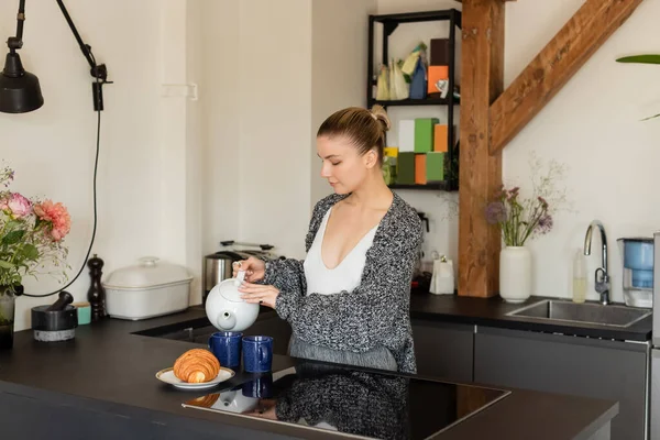 Young Woman Knitted Cardigan Pouring Tea Croissant Kitchen — Stock Photo, Image