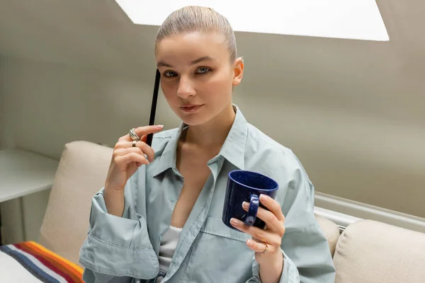 Mujer Joven Sosteniendo Pluma Taza Mientras Mira Cámara Sofá Sala — Foto de Stock