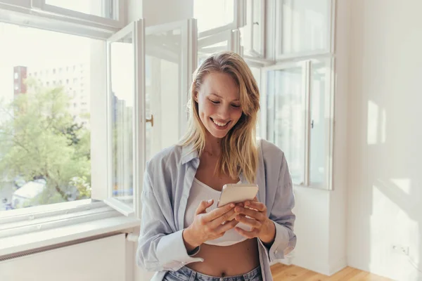 Gülümseyen Kadın Üstte Gömlekli Evde Cep Telefonu Kullanıyor — Stok fotoğraf