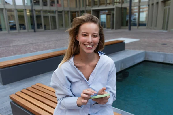 Mulher Loira Alegre Camisa Segurando Smartphone Olhando Para Câmera Banco — Fotografia de Stock
