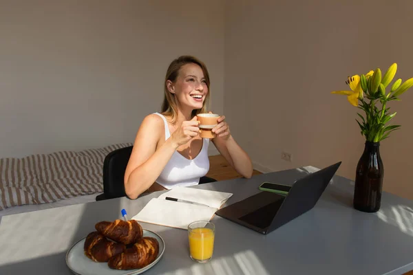 ハッピーブロンド女性保持カップ近く朝食とガジェットホーム — ストック写真