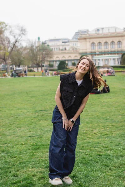 Giovane donna allegra in giacca smanicata nel parco verde dell'austria — Foto stock