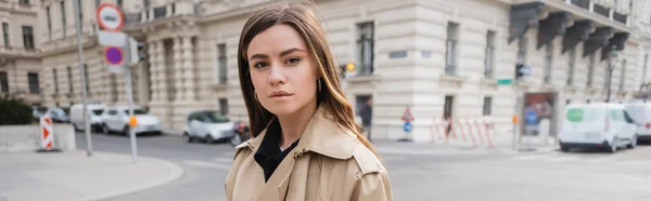 Giovane donna in trench beige in piedi su strada della città europea, striscione — Foto stock