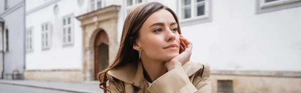 Dreamy young woman in trendy trench coat looking away, banner — Stock Photo