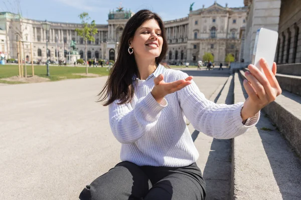 Mujer feliz tomando selfie en el teléfono inteligente, mientras que el gesto en Viena - foto de stock