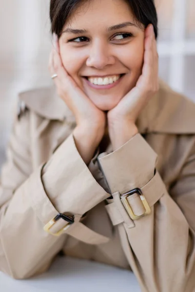 Портрет счастливой женщины в бежевом плаще, улыбающейся снаружи — стоковое фото