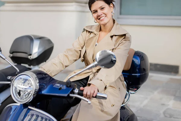 Cheerful woman in beige trench coat on scooter — Stock Photo