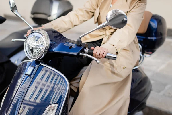 Partial view of woman in beige trench coat on scooter — Stock Photo